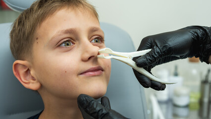 examination and examination of the nose, little boy, fair-haired teenager smiling, sitting in the...
