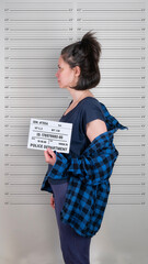 Brunette caucasian woman standing with criminal mugshot letter board at police department