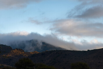 Fototapeta premium Landscape with mountains and low level fog at sunset, with space for text