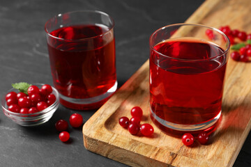 Tasty refreshing cranberry juice and fresh berries on grey textured table