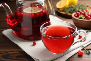 Tasty hot cranberry tea and fresh berries on wooden table
