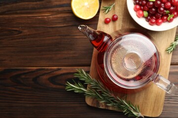 Obraz na płótnie Canvas Tasty hot cranberry tea, lemon, rosemary and fresh berries on wooden table