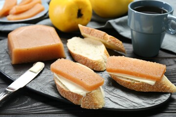 Tasty sandwiches with quince paste served on black wooden table, closeup