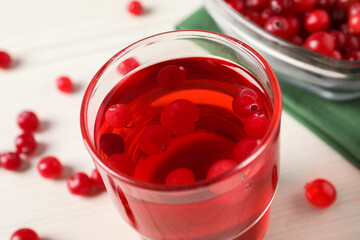 Tasty cranberry juice in glass and fresh berries on white wooden table, closeup