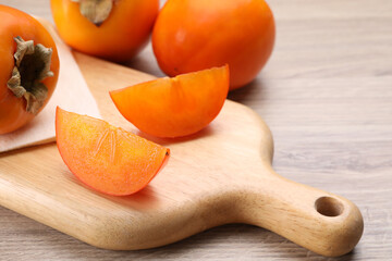 Delicious ripe persimmons on light wooden table, closeup