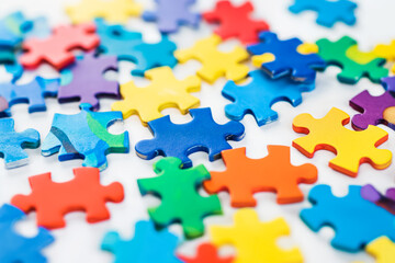 Assorted colorful jigsaw puzzle pieces scattered on a white background, with a focus on a central yellow piece.
