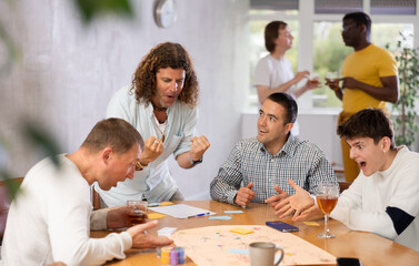 Fototapeta premium Group of men play board games during a friendly meeting indoors