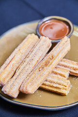 Crispy Sugar Coated Churros with Chocolate Sauce on Ceramic Plate