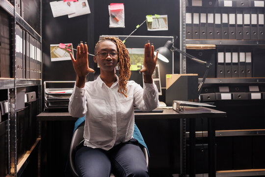 African american woman police detective using ar to visualize crime case information. Law enforcement investigator making arm gestures while brainstorming with augmented reality technology