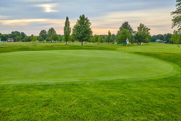 Obraz premium Serene Golf Course at Golden Hour with Mature Trees and Gentle Sky