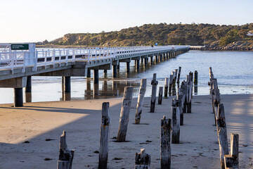 The old causeway ruins and the new causeway between Victor Harbor and Granite island on a bright sunny day in South Australia on September 11th 2023 - obrazy, fototapety, plakaty