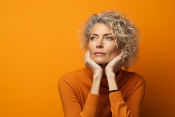 Portrait of a beautiful blonde woman with curly hair on orange background