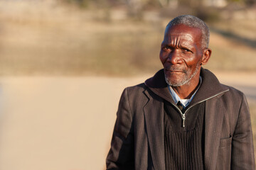 old african man standing on a dirt road in a sunny day