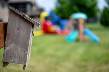 Wooden birdhouse mounted to a post in a backyard