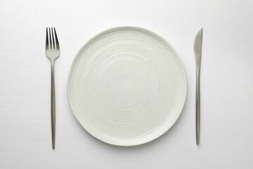 Empty plate, fork and knife on white table, top view