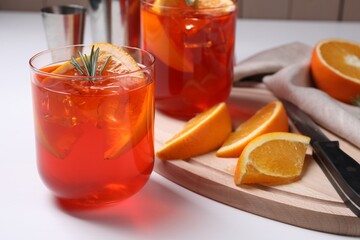 Aperol spritz cocktail, rosemary and orange slices on white wooden table, closeup