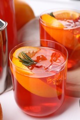 Aperol spritz cocktail, rosemary and orange slices on white table, closeup
