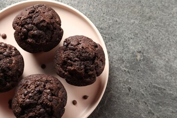 Delicious chocolate muffins on grey textured table, top view. Space for text
