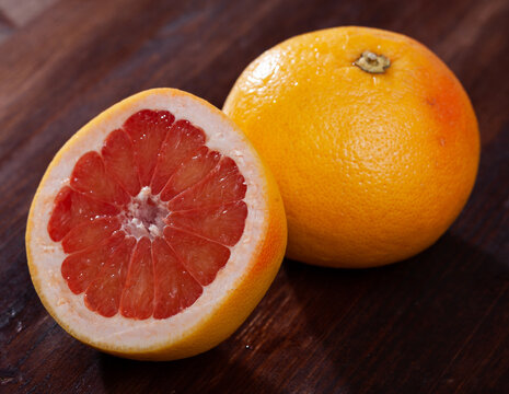 Closeup of fresh pink pomelo with chopped slices on wooden background. Vitamin product
