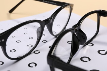 Vision test chart and glasses on table, closeup