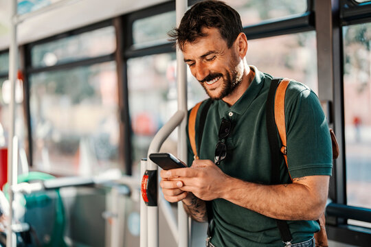 Portrait of a young man riding a public bus and typing on the phone.