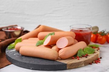 Delicious boiled sausages, basil and peppercorns on light table against white background, closeup