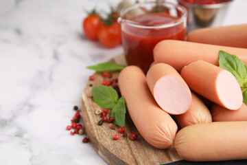 Delicious boiled sausages, basil and peppercorns on white marble table, closeup. Space for text