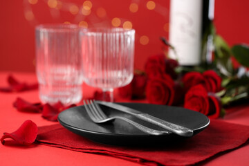Place setting with roses on red table, closeup. Romantic dinner