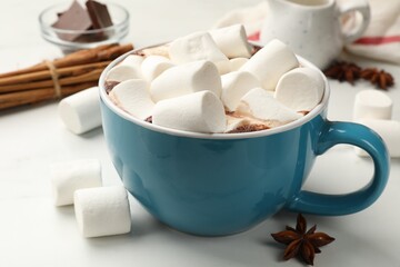 Tasty hot chocolate with marshmallows and ingredients on white table, closeup