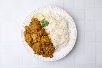 Delicious chicken curry with rice on white tiled table, top view