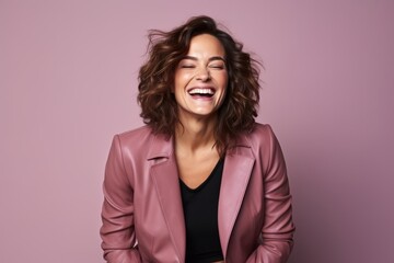Portrait of a happy young woman laughing on a pink background.