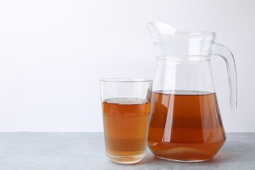 Homemade fermented kombucha in glass and jug on light grey table. Space for text
