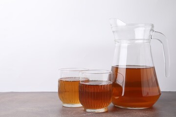 Homemade fermented kombucha in glasses and jug on grey table. Space for text