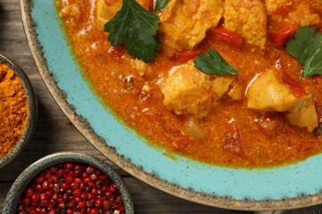 Delicious chicken curry and spices on wooden table, top view