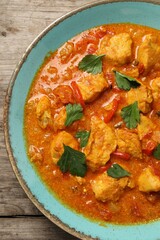Delicious chicken curry on wooden table, top view