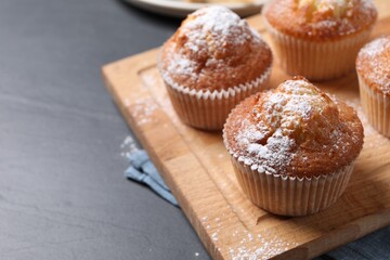 Delicious sweet muffins on black textured table, closeup. Space for text