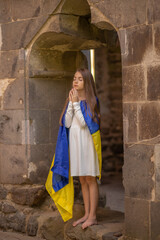 Girl praying wrapped in Ukrainian flag