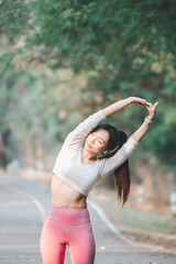 Fitness concept, Young woman in sports attire stretching her arms, enjoying her workout routine in a lush green park.