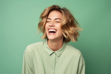 Portrait of a happy young woman laughing, isolated on green background