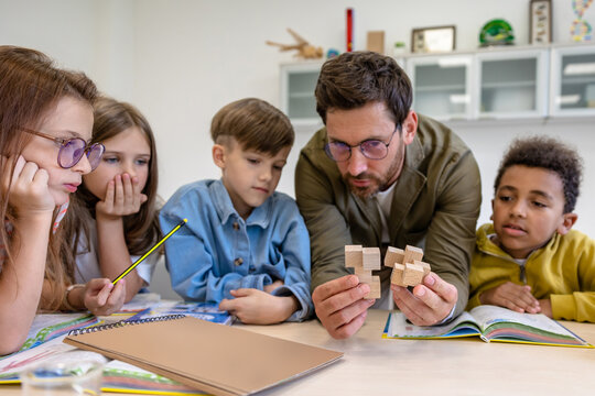 Man teacher with kids during chemistry lesson in school classroom.