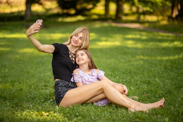 Fototapeta premium Mother and daughter taking a selfie in the park