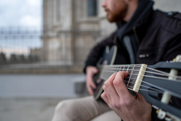 Close-up of a man's hands playing guitar sitting on the street. Music concept