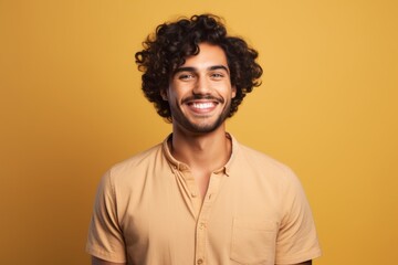 Portrait of happy young man with curly hair on yellow background.