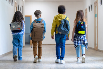 Back view of group of school kids walking in corridor.