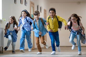 Group of elementary school kids running in school corridor.