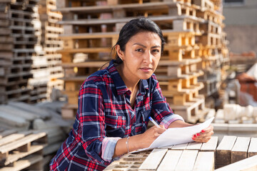 Woman manager keeps records of building materials in the open area of a construction store