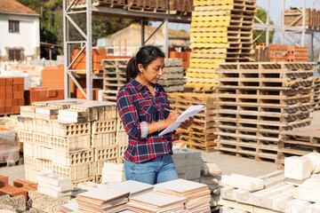 Woman manager keeps records of building materials in the open area of a construction store