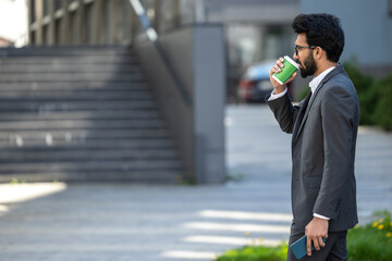Young businessman having coffee outside and feeling good