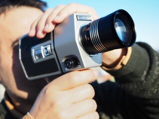 A man recording with a super 8 video camera outdoors 