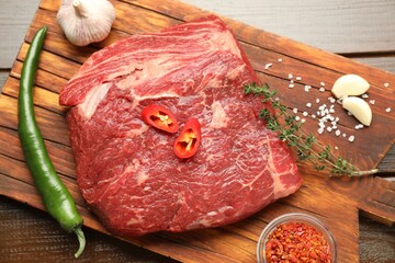 Fresh raw beef cut with spices on wooden table, top view